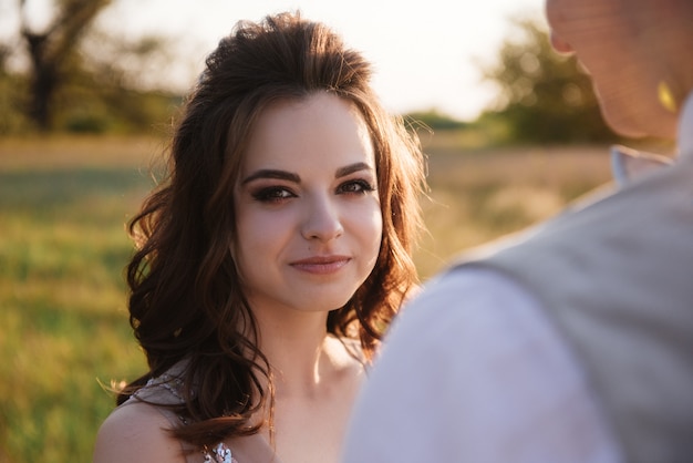 Novia y el novio posando en el campo al atardecer