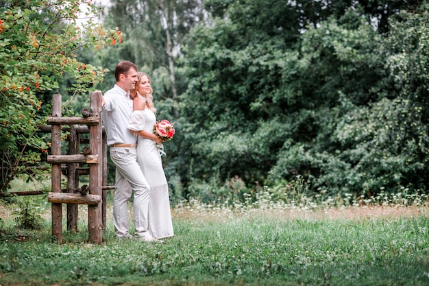 La novia y el novio posando en un campo con hierba verde