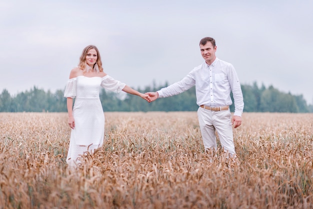 La novia y el novio posando en un campo de trigo