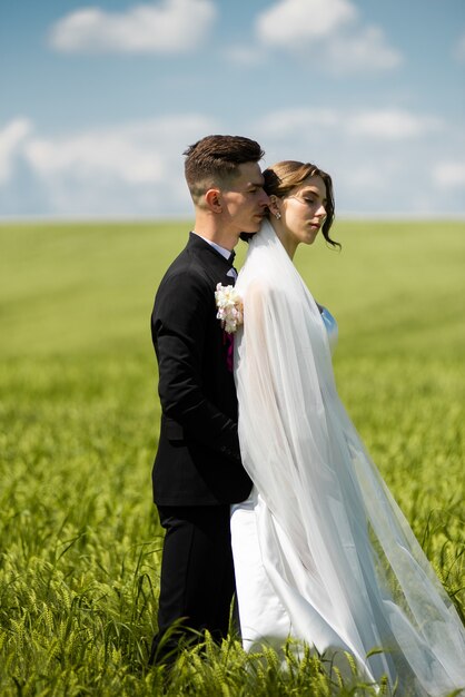 La novia y el novio posando en campo verde