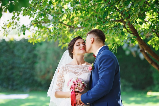 La novia y el novio posando en un parque