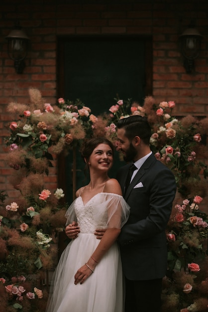 Novia y novio que abrazan cerca del arco de la boda