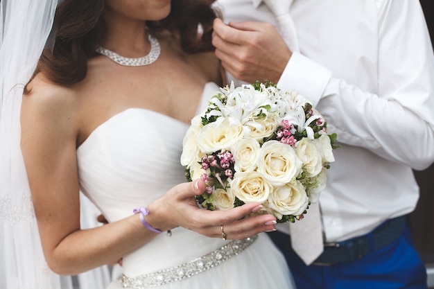 Novia y novio que sostienen un ramo de la boda