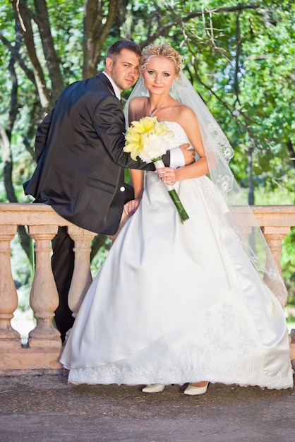 Novia y el novio con ramo de lilly amarillo en el día de la boda caminando