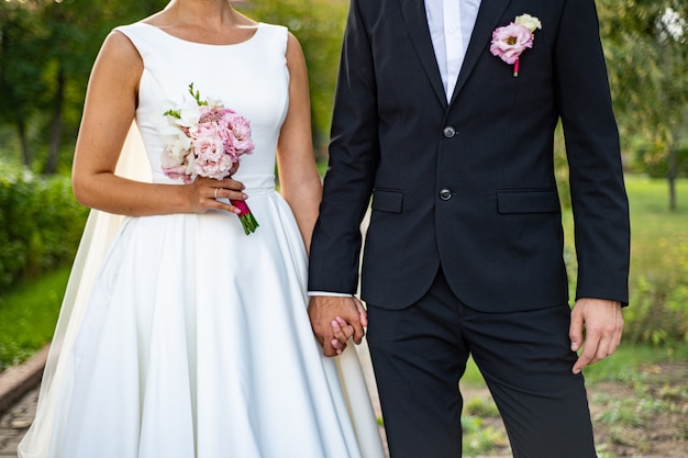 Foto novia y el novio con un ramo. la novia con un vestido blanco peludo, el novio con un traje de esmoquin azul.