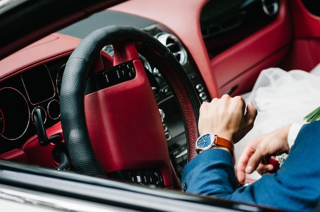 La novia y el novio recién casados en un coche retro convertible en una carretera rural para luna de miel