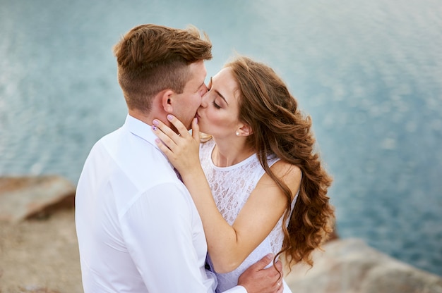Novia y el novio sentado en la playa y besándose
