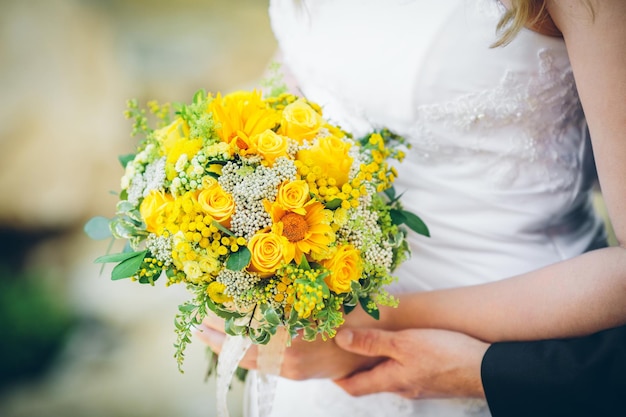 Foto novia y novio sosteniendo un ramo de girasoles