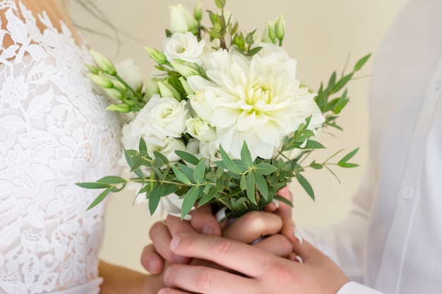 La novia y el novio sosteniendo un ramo de novia juntos, de pie frente a frente