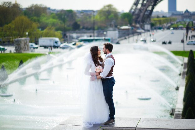 Novia y novio teniendo un momento romántico el día de su boda en París, frente a la gira Eiffel