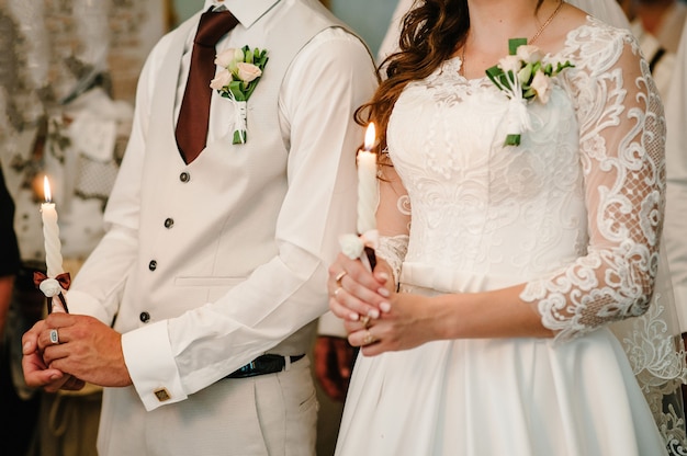 La novia, el novio tiene velas de boda en las manos. Quema la vela.