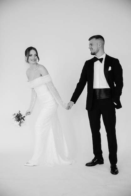 una novia y un novio se toman de la mano y posan para una foto