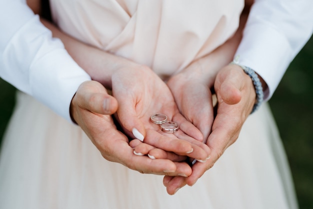 La novia y el novio se tomaron de la mano con anillos de boda.