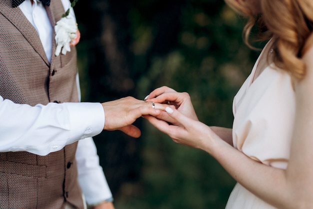 La novia y el novio se tomaron de la mano con anillos de boda.