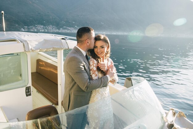 La novia y el novio con traje de boda navegan en un yate en el lago de Como en Italia