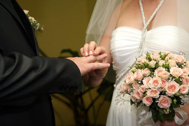 La novia y el novio usan anillos de boda entre sí