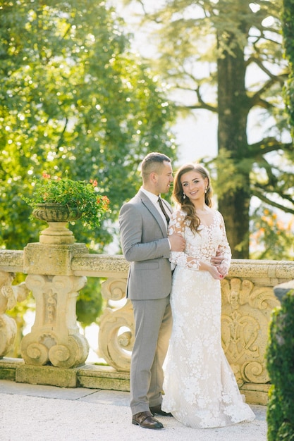 novia y novio velo largo y vestido blanco sobre fondo de montañas lago de Como Italia