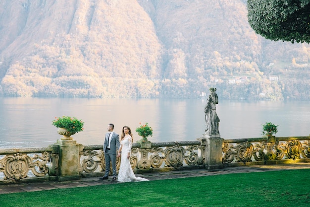 novia y novio velo largo y vestido blanco sobre fondo de montañas lago de Como Italia