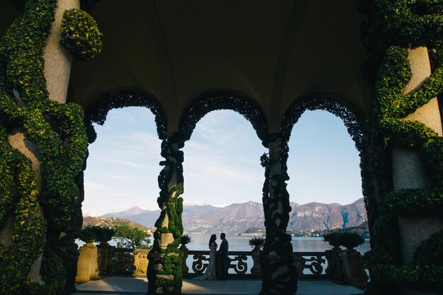 novia y novio velo largo y vestido blanco sobre fondo de montañas lago de Como Italia