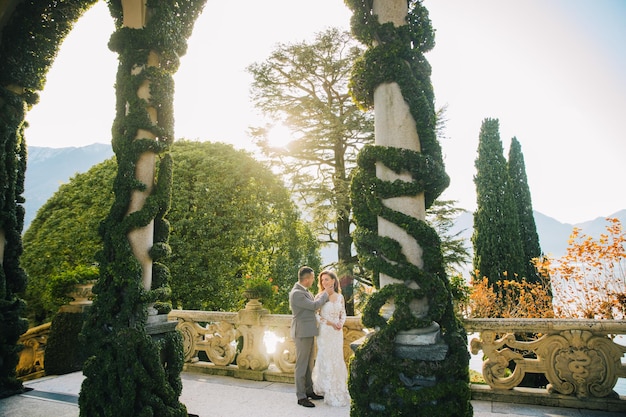 novia y novio velo largo y vestido blanco sobre fondo de montañas lago de Como Italia