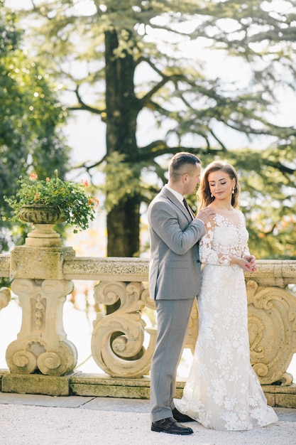 novia y novio velo largo y vestido blanco sobre fondo de montañas lago de Como Italia