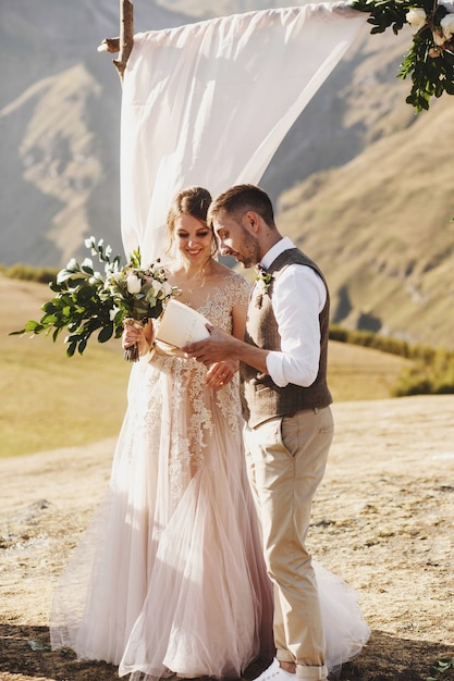 La novia y el novio se ven hermosos durante la ceremonia de la boda en la cima de la montaña