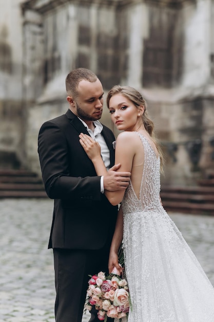 La novia y el novio se ven impresionantes posando cerca de la antigua iglesia