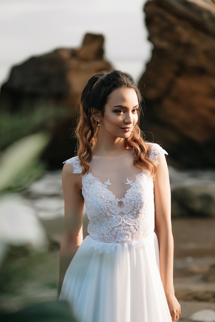 Novia en la orilla del mar negro a la luz del atardecer