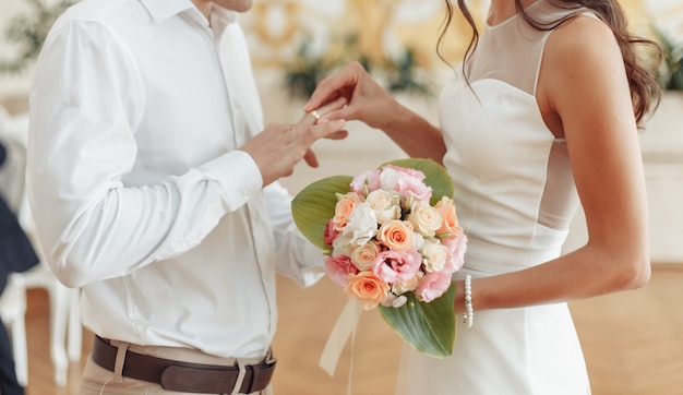 La novia pone un anillo de oro en el dedo del novio. ceremonia de la boda