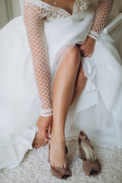 Una novia para ponerse los zapatos de boda. Primer plano de hermosos pies femeninos.