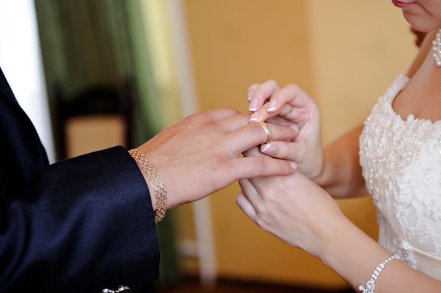 Novia poniendo un anillo de bodas en el dedo del novio