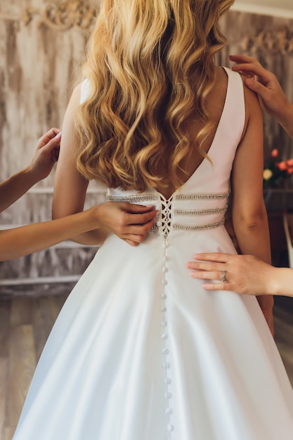 Novia poniéndose su vestido de novia blanco. Concepto de celebración de boda.