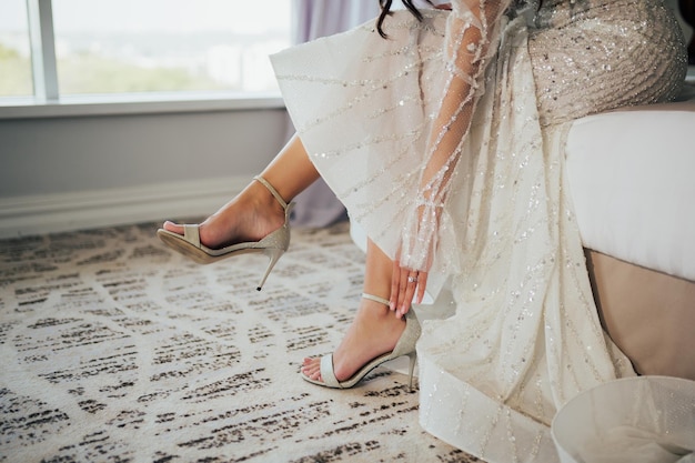 Novia poniéndose sus elegantes sandalias plateadas