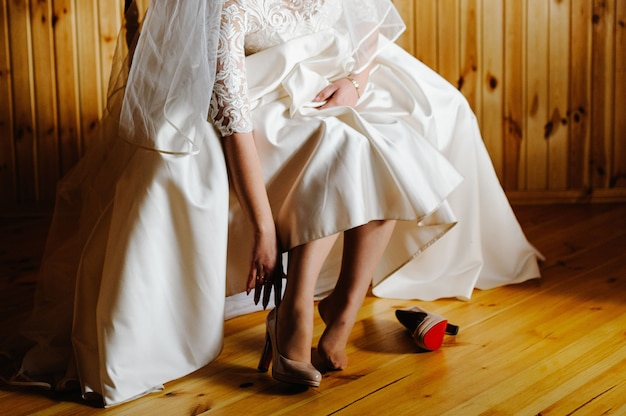 Foto novia poniéndose sus elegantes zapatos beige lacados clásicos.