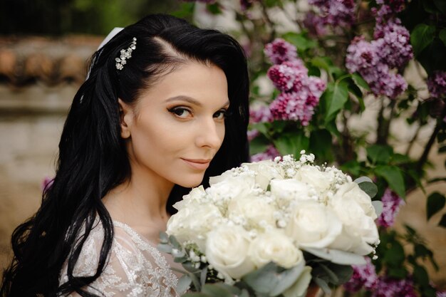 Una novia posa frente a flores moradas