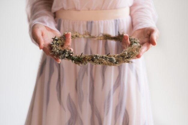 Novia que sostiene una guirnalda floral de flores secas. Fondo blanco en el estudio. mañana de la novia