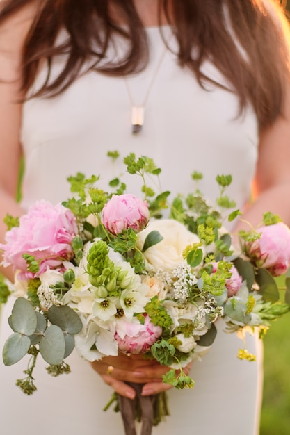 Novia que sostiene un ramo de la boda en colores rosados en colores pastel.