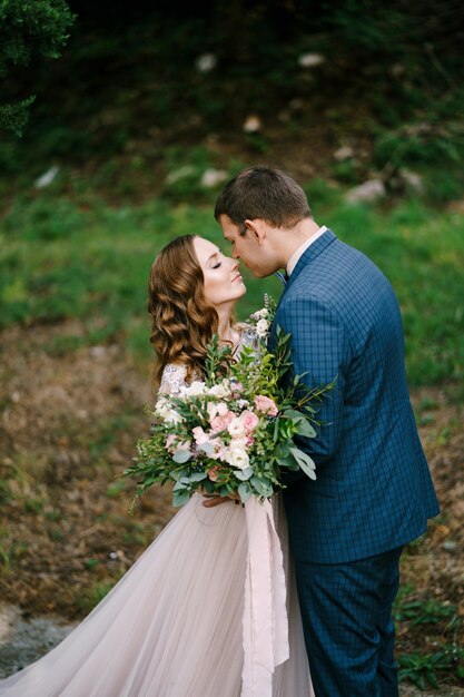 La novia con un ramo casi besa al novio en el jardín.