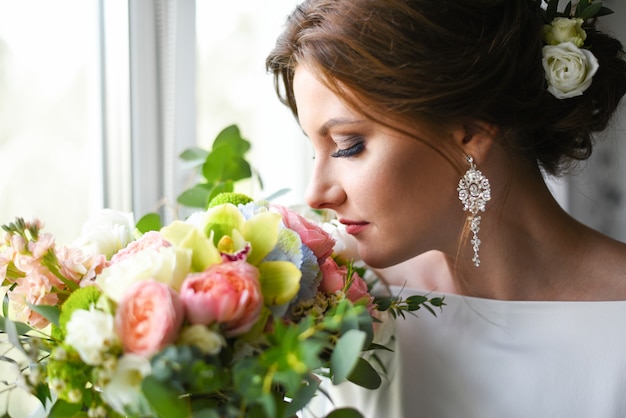 Novia con un ramo esperando al novio cerca de la ventana