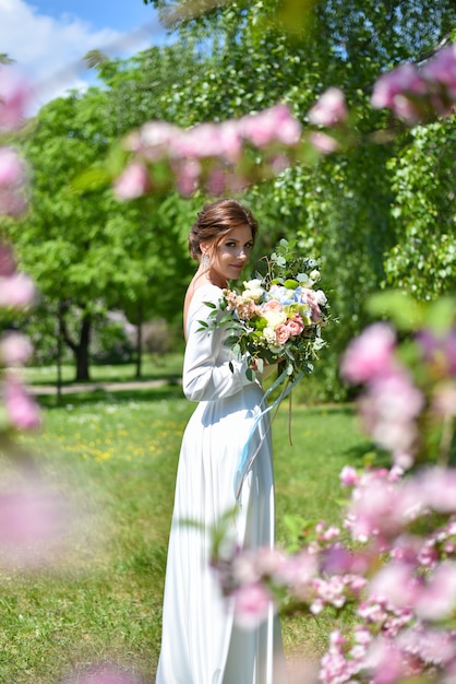 Novia con un ramo de flores en el parque de verano