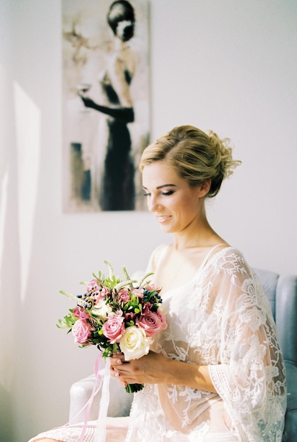 La novia con un ramo de flores se sienta en una silla