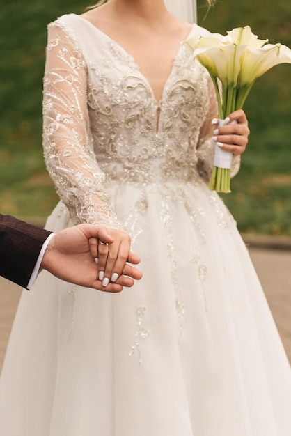 La novia con un ramo de novia blanco sostiene la mano del novio en la ceremonia de boda