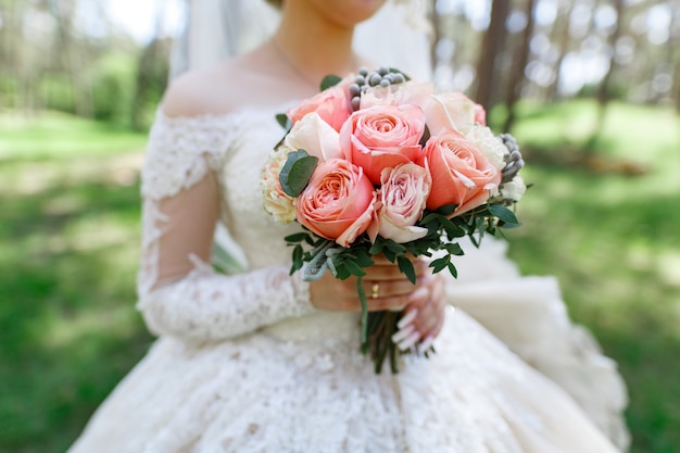 novia con un ramo de rosas rosadas al aire libre.