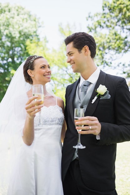 Novia romántica y el novio con champán en el parque