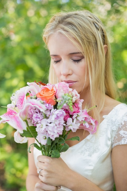 Novia rubia que huele su ramo colorido