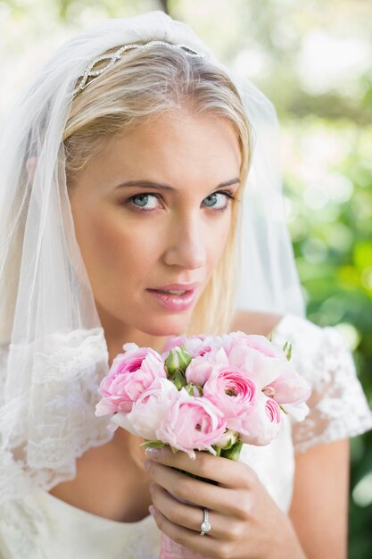 Novia rubia en un velo con su ramo de rosas