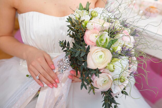 Novia sentada en un banco con ramo de novia de varias flores