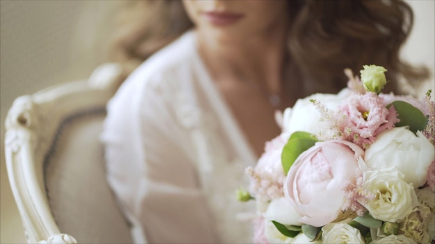 Una novia sentada en una silla con su ramo de rosas.