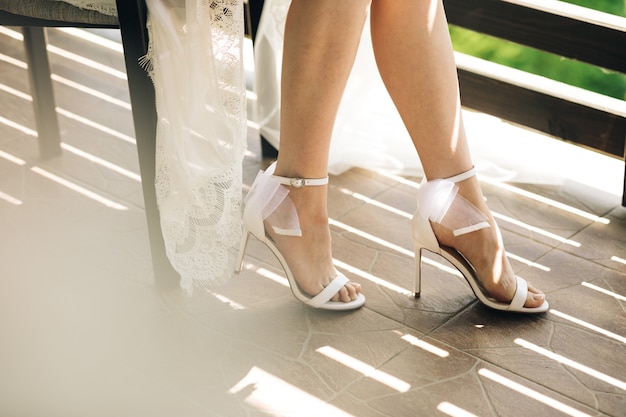 Foto novia sentada con vestido de novia y tacones altos