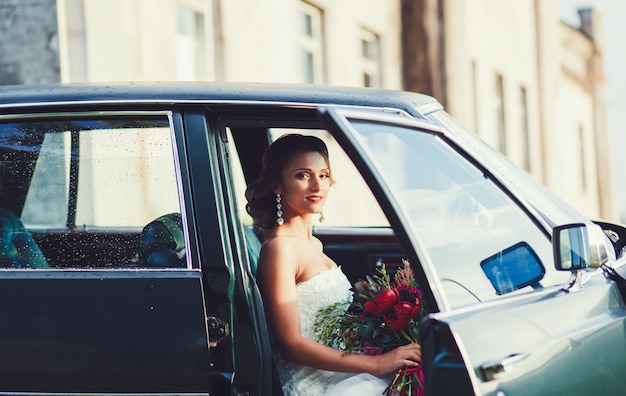 La novia se sienta en un auto el día de la boda